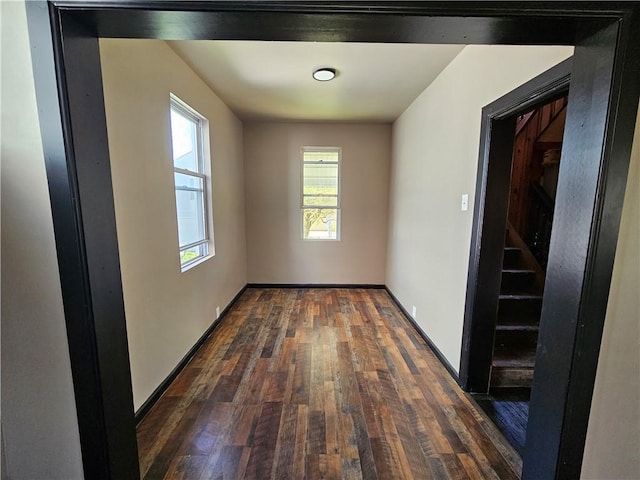 unfurnished room featuring baseboards and dark wood-type flooring