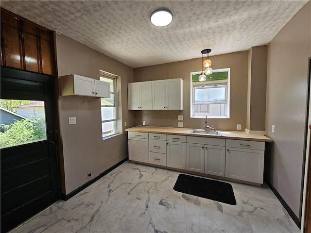 kitchen featuring marble finish floor, a sink, and baseboards