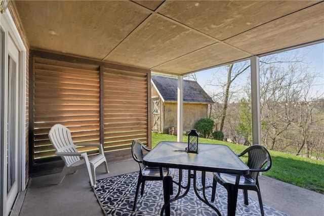 view of patio featuring an outdoor structure, outdoor dining space, and a shed