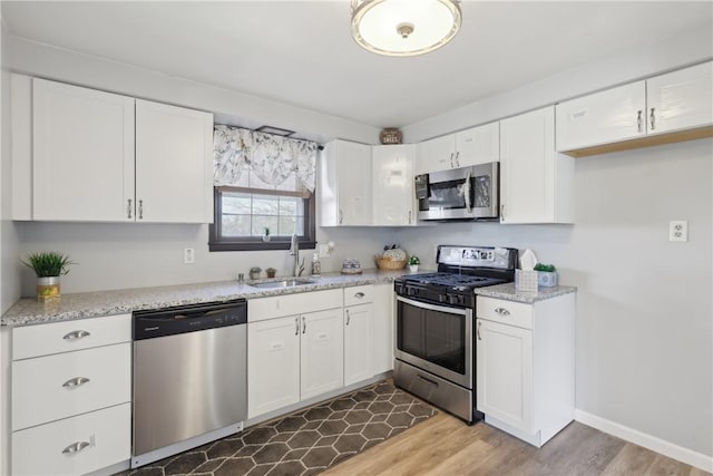 kitchen featuring appliances with stainless steel finishes, white cabinetry, and a sink