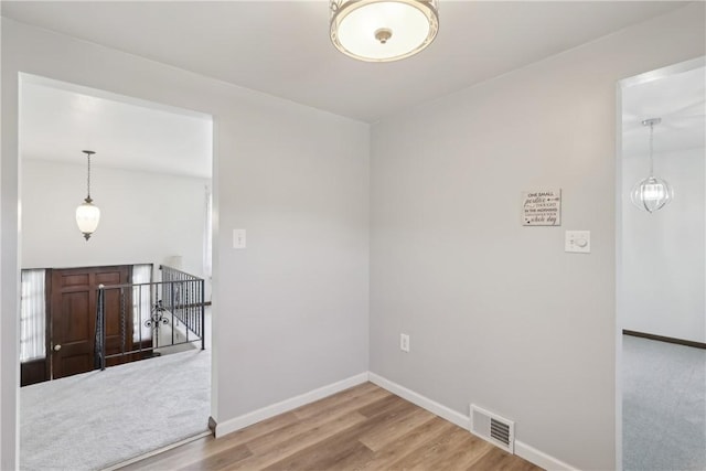 empty room featuring baseboards, wood finished floors, and visible vents