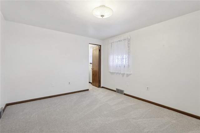 unfurnished room with visible vents, baseboards, and light colored carpet