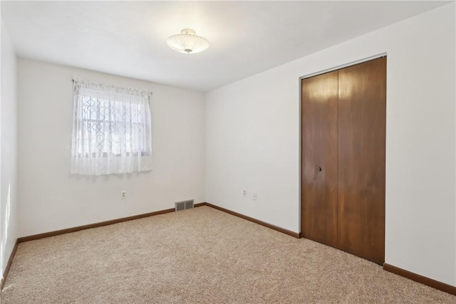 unfurnished bedroom with baseboards, carpet flooring, visible vents, and a closet