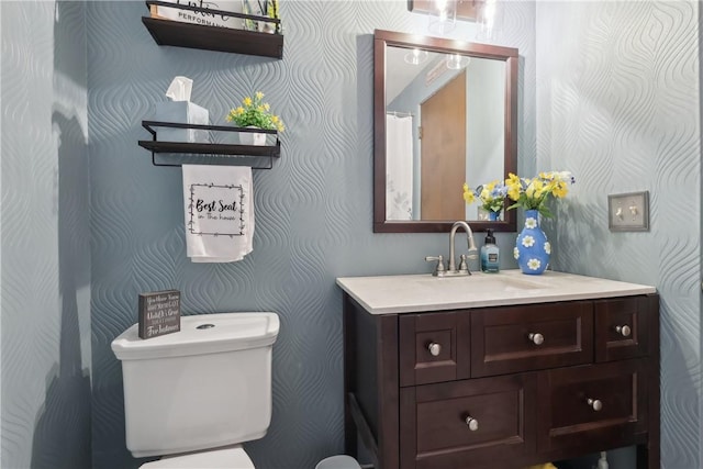 bathroom with wallpapered walls, vanity, and toilet