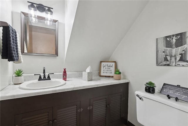 bathroom with lofted ceiling, toilet, and vanity