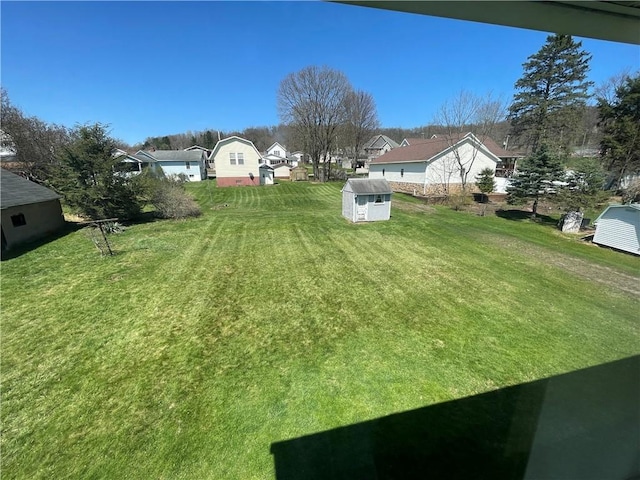 view of yard with a storage shed, a residential view, and an outbuilding