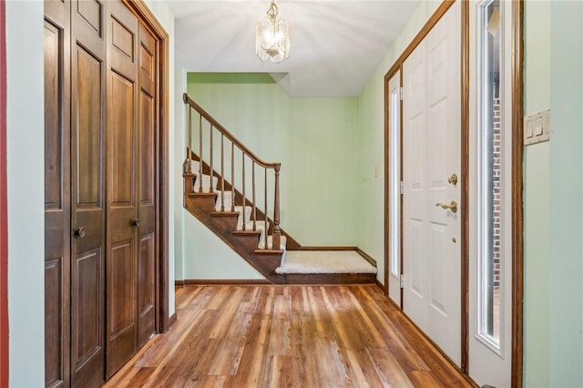 entrance foyer featuring stairs, an inviting chandelier, wood finished floors, and baseboards