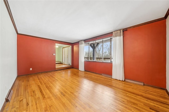 unfurnished room featuring a baseboard radiator, baseboards, hardwood / wood-style flooring, and ornamental molding