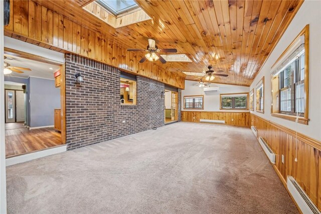 unfurnished living room with a skylight, a ceiling fan, and a baseboard radiator