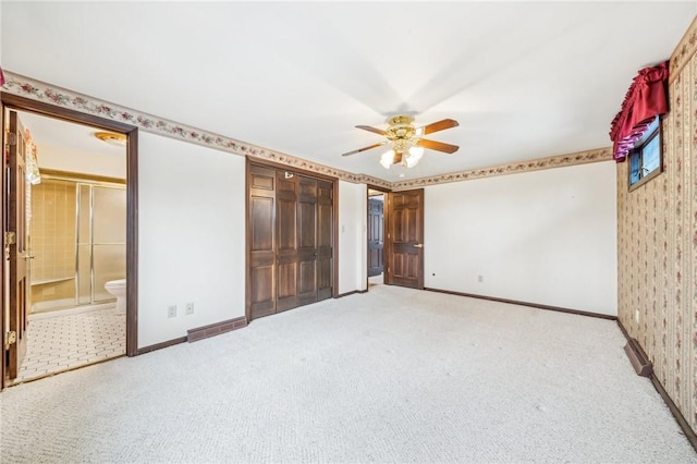 unfurnished bedroom featuring light colored carpet, baseboards, a ceiling fan, and ensuite bathroom
