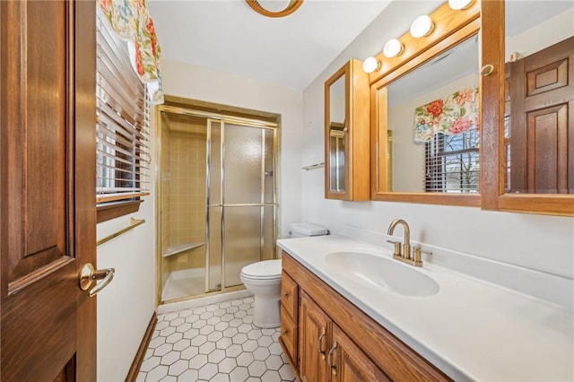 bathroom featuring toilet, vanity, and a stall shower