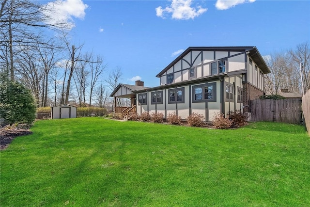 back of property featuring fence, stucco siding, a shed, an outdoor structure, and a lawn