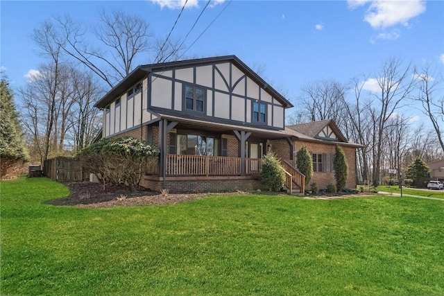 rear view of house featuring brick siding, a yard, and covered porch