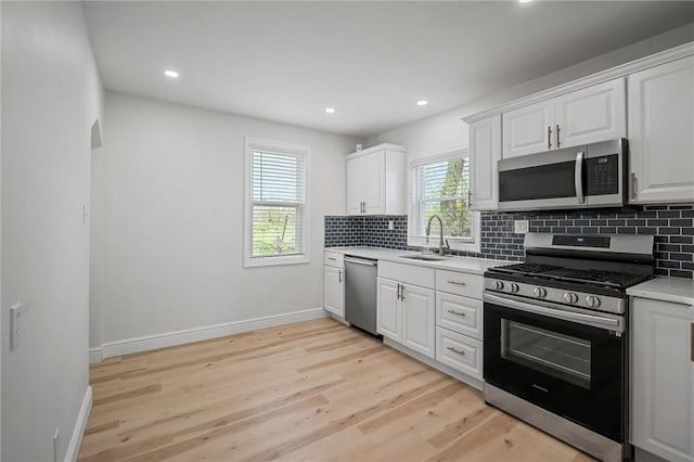 211 Wainwright Ave, Brentwood, PA 15227 - kitchen featuring light wood finished floors, stainless steel appliances, a sink, backsplash, and white cabinetry