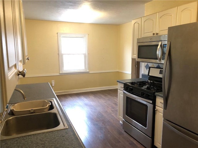 159 Oakville Rd, Chippewa Twp, PA 15010 - kitchen with stainless steel appliances, a sink, dark countertops, dark wood-style flooring, and white cabinetry
