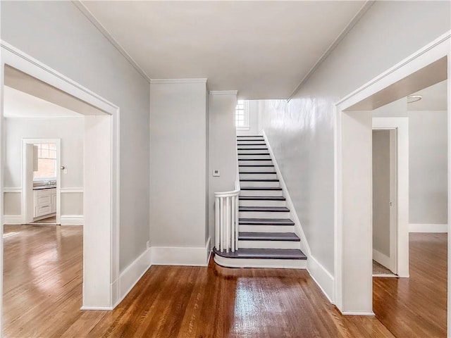 staircase featuring baseboards, wood finished floors, and a wealth of natural light