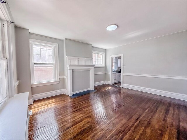 unfurnished living room featuring dark wood finished floors and baseboards