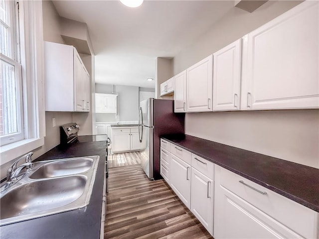 kitchen with white cabinets, appliances with stainless steel finishes, a sink, and dark countertops