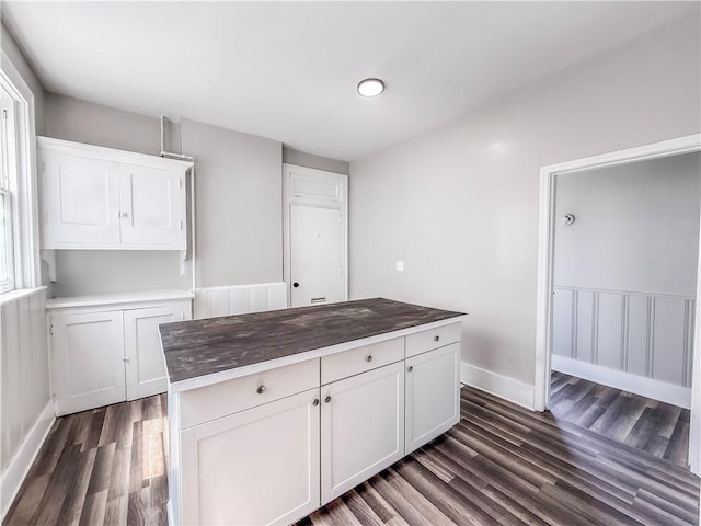 kitchen featuring white cabinets, dark wood finished floors, baseboards, and wooden counters