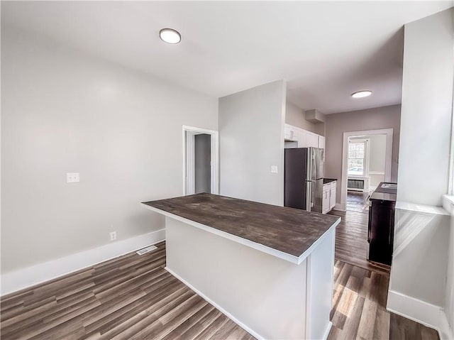 kitchen featuring white cabinets, dark wood-type flooring, freestanding refrigerator, baseboards, and wood counters