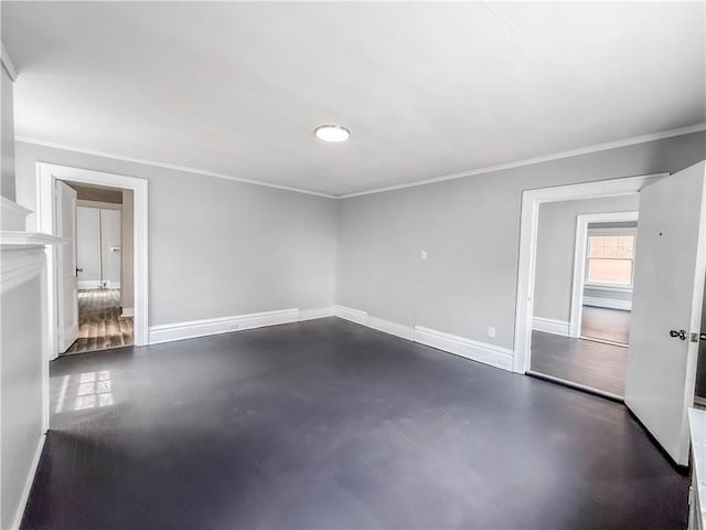 spare room with concrete flooring, ornamental molding, and baseboards