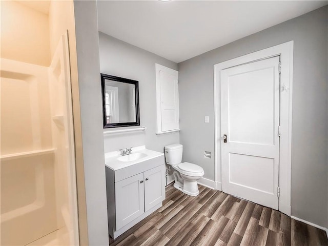 bathroom featuring baseboards, wood finished floors, toilet, and vanity