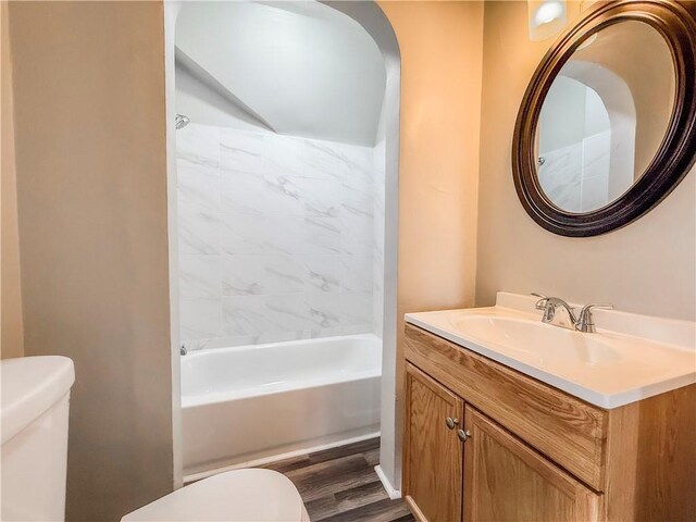full bath with wood finished floors, vanity, washtub / shower combination, and toilet