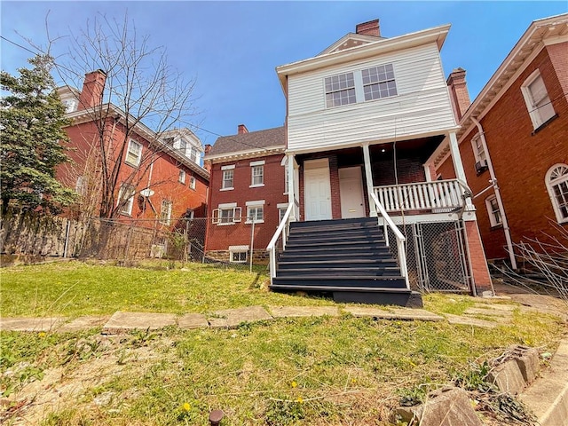 back of property with stairway, a chimney, fence, a yard, and brick siding