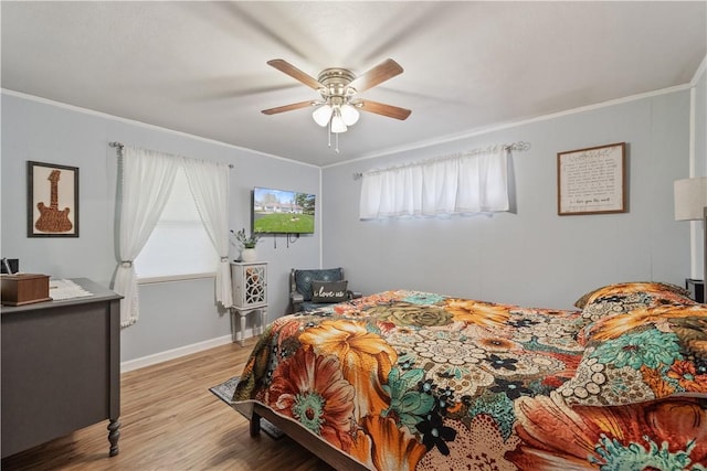 bedroom with ceiling fan, baseboards, crown molding, and light wood-style flooring