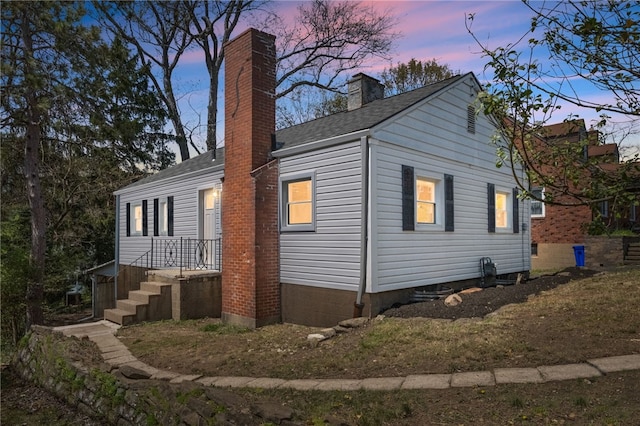 view of side of home with a shingled roof and a chimney
