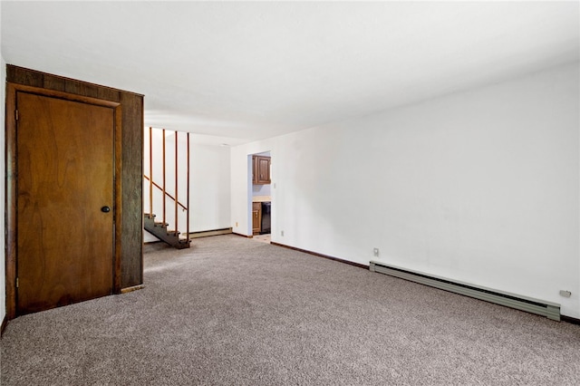 spare room with a baseboard heating unit, stairway, baseboards, and light carpet