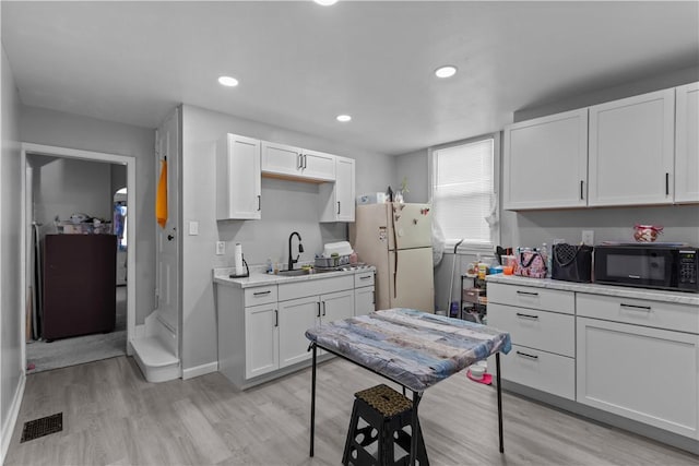 833 Stanton Ave, Millvale, PA 15209 - kitchen featuring a sink, black microwave, light wood-style flooring, visible vents, and freestanding refrigerator