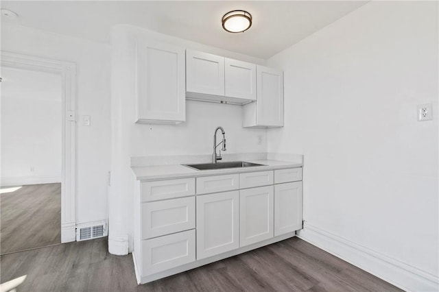 216 Ridge Ave, New Kensington, PA 15068 - kitchen featuring light countertops, dark wood-style floors, white cabinetry, and a sink