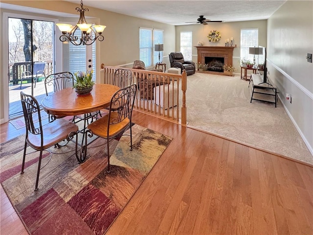 827 Boulder Dr, Bethel Park, PA 15102 - dining room featuring a fireplace, ceiling fan with notable chandelier, baseboards, and wood finished floors