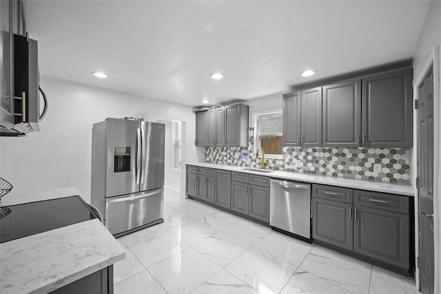 kitchen with stainless steel appliances, a sink, recessed lighting, decorative backsplash, and gray cabinetry