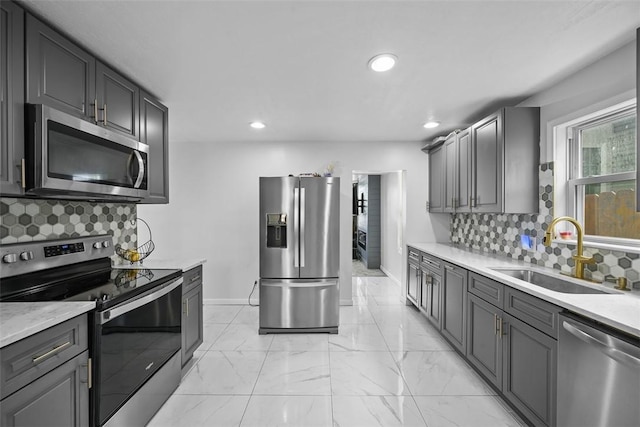 kitchen featuring appliances with stainless steel finishes, baseboards, decorative backsplash, and a sink