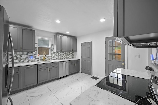 kitchen featuring recessed lighting, marble finish floor, gray cabinets, a sink, and appliances with stainless steel finishes