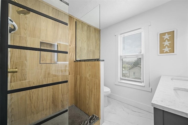 full bath featuring a tile shower, marble finish floor, toilet, vanity, and baseboards