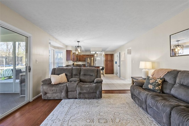 158 Edgemeade Dr, Monroeville, PA 15146 - living room with an inviting chandelier, light wood-style floors, a textured ceiling, and baseboards