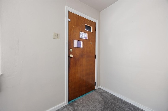 doorway featuring carpet flooring and baseboards