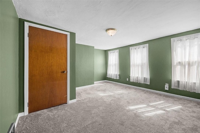 carpeted empty room featuring baseboards and a textured ceiling