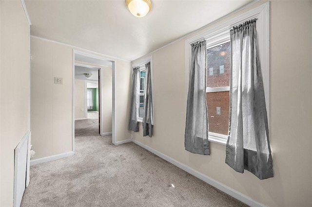 spare room featuring carpet floors, baseboards, and ornamental molding