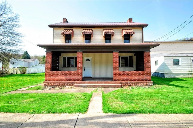 view of front of property with a porch, a front lawn, a chimney, and brick siding