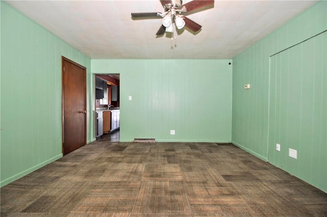 spare room with dark carpet and ceiling fan