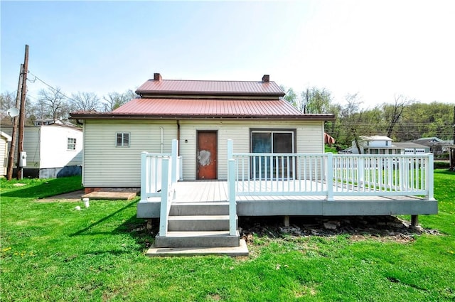 back of house with a yard, a chimney, metal roof, and a deck