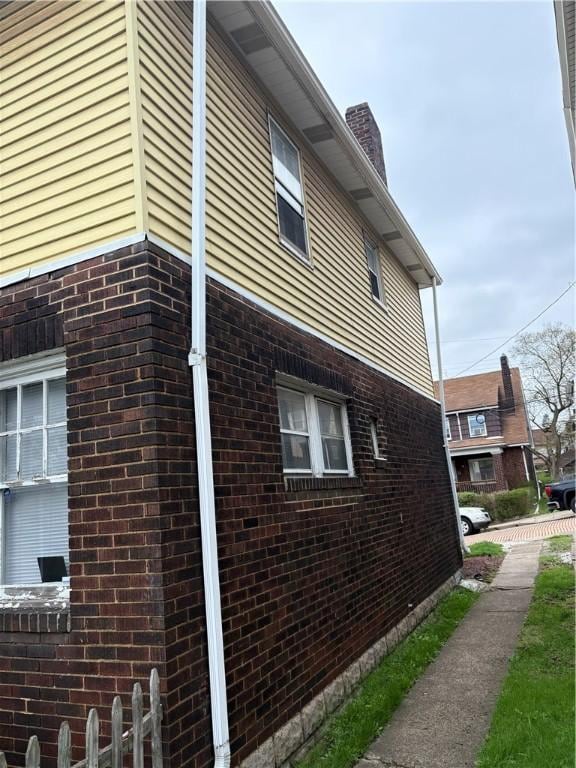 view of home's exterior with a chimney and brick siding