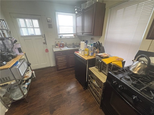 kitchen featuring black gas stove, a sink, fridge, light countertops, and dark wood-style floors