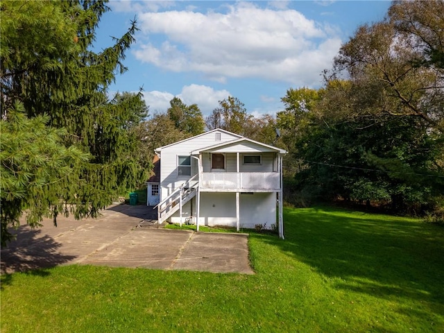 rear view of house with a lawn, stairway, and a porch