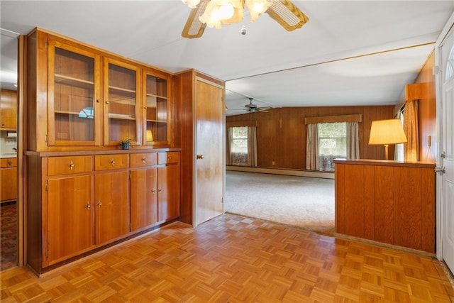 unfurnished living room featuring wood walls, baseboard heating, and ceiling fan