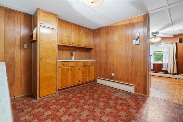 kitchen with baseboard heating, brown cabinets, wood walls, and a ceiling fan